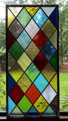 a colorful stained glass window with trees in the background