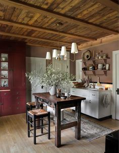 a kitchen with wooden floors and white appliances in the center, along with an old - fashioned dining table surrounded by stools