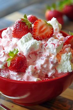 a red bowl filled with strawberries and whipped cream