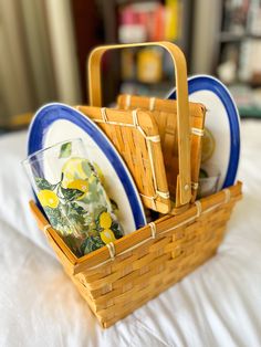 a basket filled with plates and bowls on top of a bed