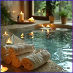 two towels are sitting on the edge of a pool with candles in front of it