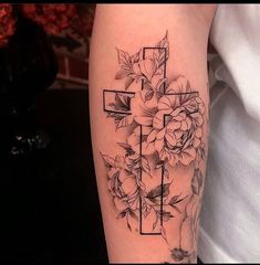 a cross and flowers tattoo on the arm