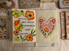 an open notebook with flowers and words on the pages next to other items that have been altered