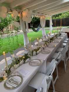 a long table set up with plates and candles for an outdoor dinner or party event