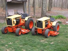 two orange tractors sitting in the grass