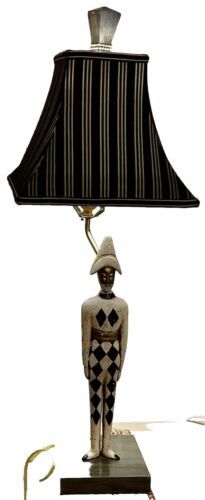 a table lamp with a black and white striped shade on it's face, sitting on a wooden base