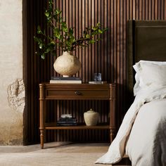 a bedroom with a bed, nightstand and potted plant on the end table next to it