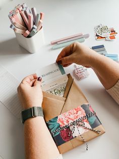 a person is wrapping up an envelope on a table with other papers and stationery