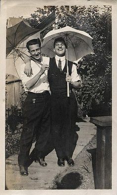 an old black and white photo of two people holding umbrellas in their hands while standing next to each other