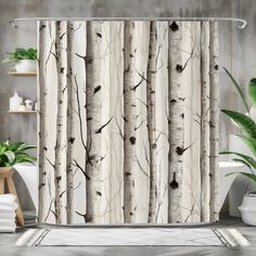 a shower curtain with trees on it in a bathroom next to a potted plant