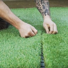 a man laying on top of a lush green field next to a pile of fake grass