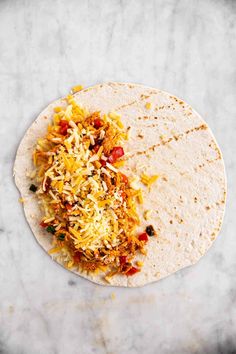 a tortilla with shredded meat and vegetables on it