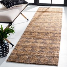 a living room area with a chair and rug on the floor, windows in the background