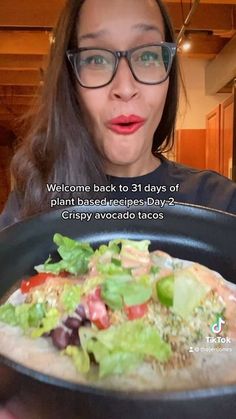 a woman is holding a plate with a salad on it that says welcome back to 31 days of plant based celery avocado tacos