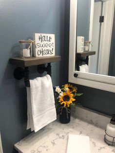 a white sink sitting under a bathroom mirror next to a wooden shelf filled with towels