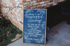 a chalkboard sign sitting on the side of a brick wall next to a bench