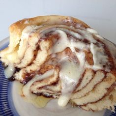 a cinnamon roll with icing on a blue and white plate