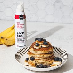 a stack of pancakes on a plate with bananas and blueberries next to the package