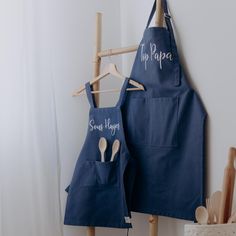 two blue aprons hanging up against a wall