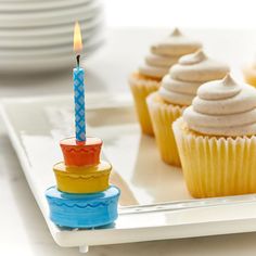 a cupcake with a lit candle on it sitting in front of other cupcakes