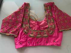 Pink Pattu silk Maggam blouse with bell motifs and kundan work on neckline and sleeves. Note - Doris and Latkans provided are complementary so please do not complain about them. We do our best to put best latkans for you. Disclaimer - Actual colors may vary slightly due to computer monitors displaying settings. We try hard to match exact color. For sizes 42+ we charge extra $20 for fabric and workmanship. Please contact us before placing order, we will send you link to pay extra $20. Designer Pink Traditional Festive Wear, Designer Pink Traditional Wear For Festive Occasion, Pink Blouse With Mirror Work In Traditional Drape, Pink Blouse With Mirror Work And Traditional Drape, Designer Pink Traditional Wear With Traditional Drape, Silk Pink Blouse With Mirror Work, Pink Silk Blouse With Mirror Work, Designer Pink Traditional Wear With Zari Work, Pink Silk Blouse Piece With Mirror Work