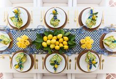 an overhead view of a table with plates and lemons on it, surrounded by yellow flowers