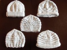 four white knitted hats sitting on top of a brown table next to each other