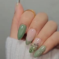 a woman's hand with some green and white nail polishes on her nails