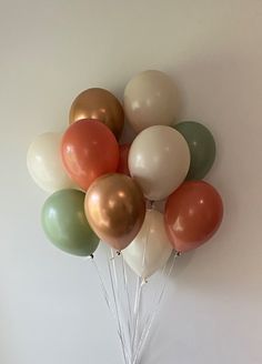 a bunch of balloons are hanging on the wall in front of a potted plant