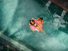 two women are floating on an inflatable raft at the edge of a pool