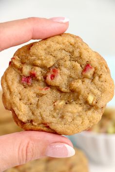 a close up of a person's hand holding a cookie with cranberry toppings