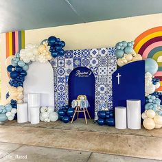 a room decorated with blue and white balloons, an arch shaped like a door and a cross on the wall