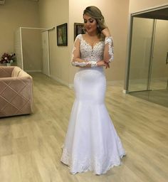 a woman in a white wedding dress looking at her cell phone while standing on the floor