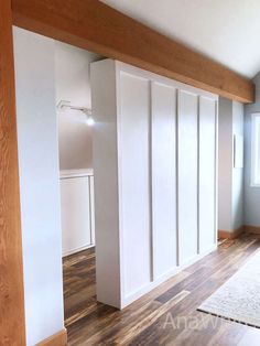 an empty room with white closets and wood flooring in front of a window