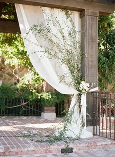 an outdoor ceremony with white drapes and greenery