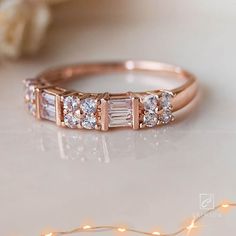 a rose gold wedding band with three baguettes on the side, surrounded by string lights