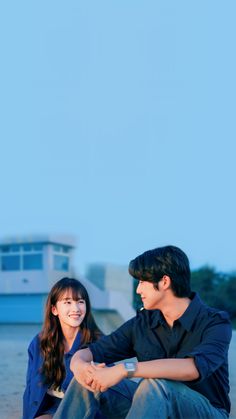 a man and woman sitting next to each other on the beach