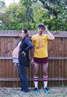 two people standing next to each other near a fence