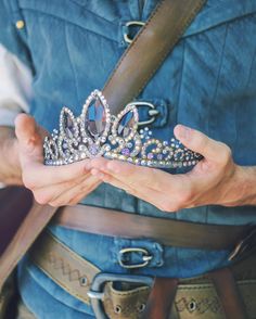 a person wearing a tiara and belt holding out their hand to show the crown