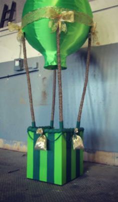 a green and black box with two large balloons attached to it's sides in front of a wall