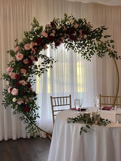 the table is set up with flowers and greenery for an elegant wedding reception in front of a curtained window