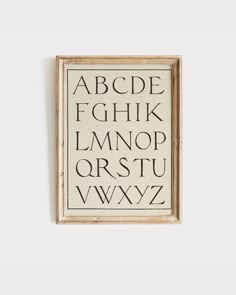 an old fashioned alphabet is hanging on the wall in front of a white wall with black letters