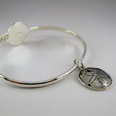 "This sterling silver Scallop Shell Bangle features a silver band with a ridged, gold vermeil scallop shell. The bangle accommodates large spacer beads and traditional charms. Marked Brown County Silver and Sterling inside the band. Also marked S.W.P. for designer Steven Wesley Patterson. Brand new, never worn condition. Available in medium only. Medium - 7.25\" Approximate weight is 14 grams *Sand dollar charm sold separately." Adjustable Silver Bracelet With Ocean-inspired Style, Adjustable Silver Bracelets With Ocean-inspired Style, Adjustable Silver Ocean-inspired Bracelets, Silver Adjustable Ocean-inspired Bracelets, Adjustable Silver Jewelry With Starfish Charm, Adjustable Silver Charm Bracelet With Starfish, Adjustable Silver Shell-shaped Jewelry, Adjustable Sterling Silver Shell-shaped Jewelry, Adjustable Shell-shaped Sterling Silver Jewelry