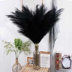 a vase filled with black feathers sitting on top of a table next to a clock