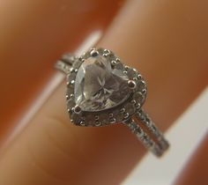 a close up view of a diamond ring on someone's finger, with the center stone surrounded by filigrees