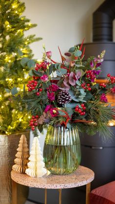 a vase filled with flowers sitting on top of a table next to a christmas tree