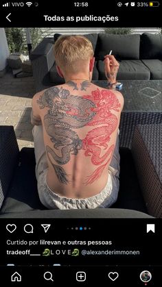 a man sitting on top of a couch next to a table with tattoos on his back