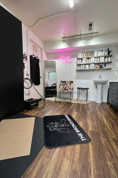 the inside of a hair salon with wood flooring and black accessories on display in front of a mirror