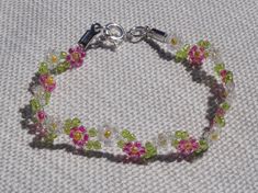 a bracelet with flowers on it sitting on top of a white cloth covered tablecloth