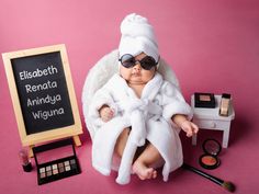 a baby in a bathrobe sitting next to makeup